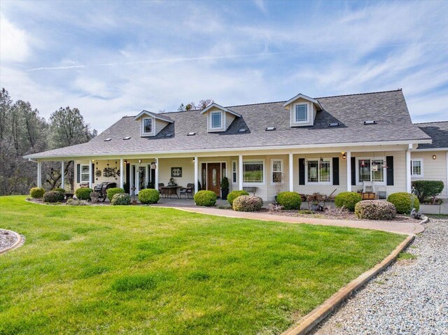 view of front of house with a shingled roof, a front lawn, and a patio area