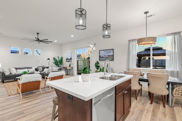 kitchen featuring light wood-type flooring, light countertops, dishwasher, and a sink