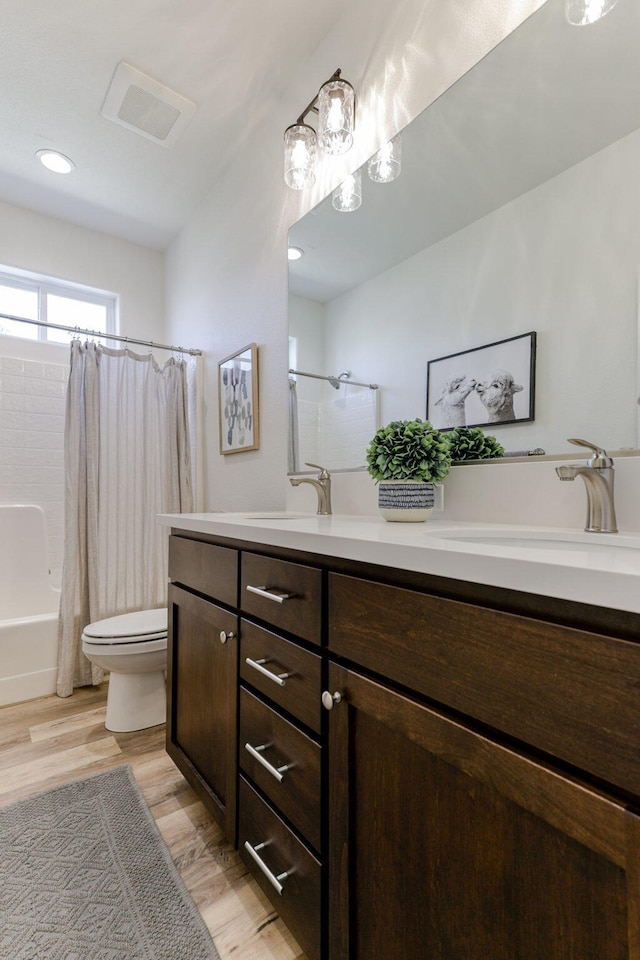 bathroom with shower / bath combo, visible vents, toilet, wood finished floors, and vanity