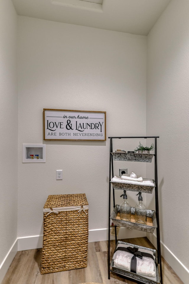 clothes washing area with hookup for a washing machine, light wood-type flooring, laundry area, and baseboards