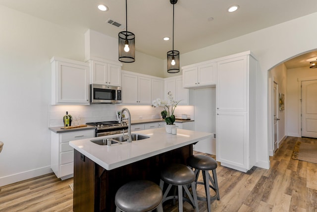 kitchen featuring visible vents, decorative backsplash, arched walkways, stainless steel appliances, and a sink