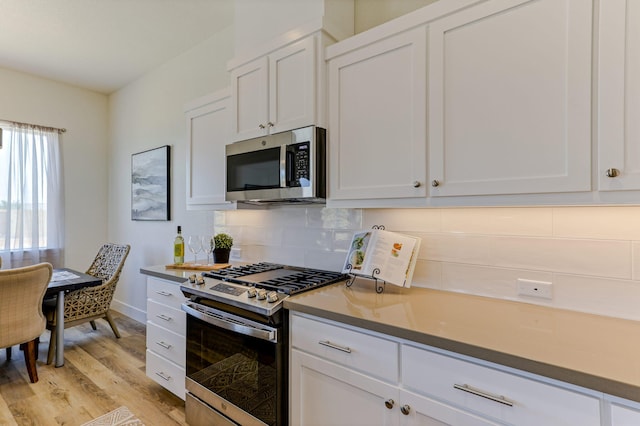 kitchen with tasteful backsplash, light wood-style flooring, appliances with stainless steel finishes, white cabinetry, and baseboards