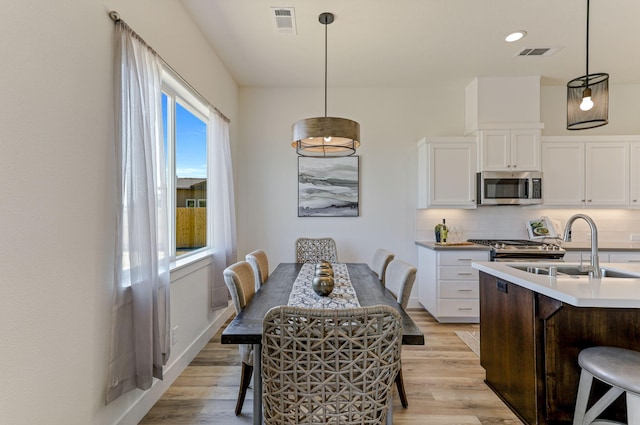 kitchen with white cabinets, stainless steel microwave, backsplash, and light wood finished floors