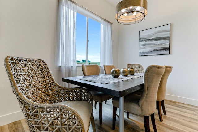 dining room with baseboards, light wood finished floors, and an inviting chandelier