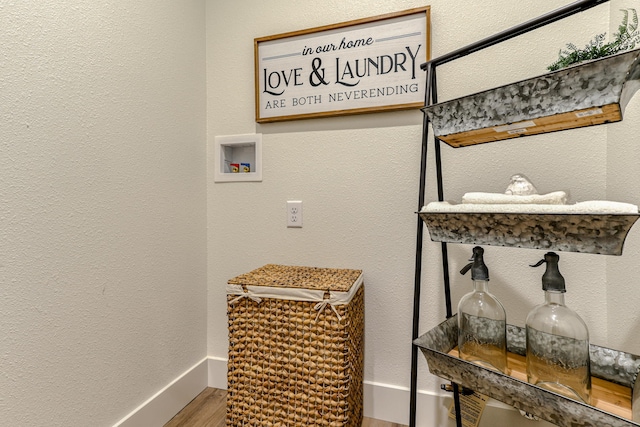 laundry area with laundry area, baseboards, a textured wall, wood finished floors, and washer hookup