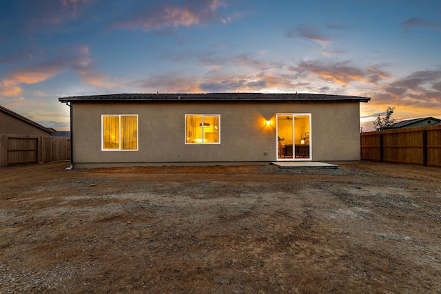 back of property at dusk with a patio area and a fenced backyard