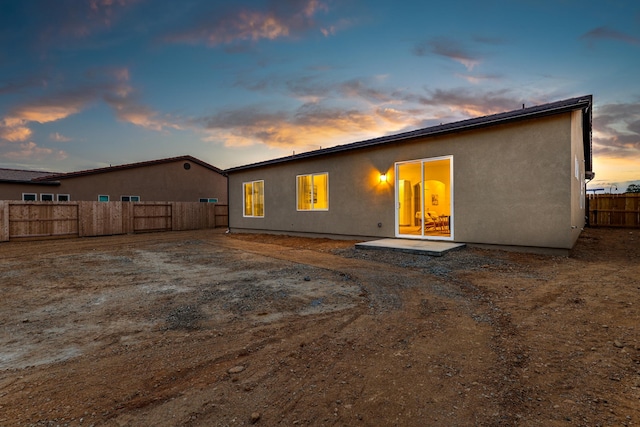 back of house with a fenced backyard and stucco siding