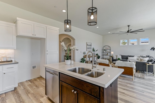 kitchen featuring arched walkways, white cabinets, a sink, and stainless steel dishwasher