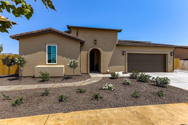 view of front of property with a garage, concrete driveway, fence, and stucco siding