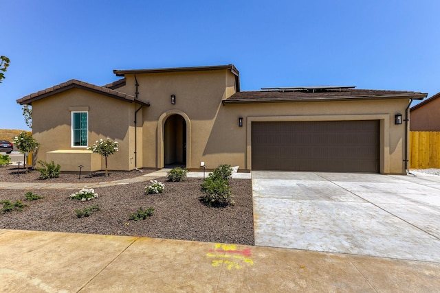 view of front of property featuring an attached garage, driveway, solar panels, and stucco siding