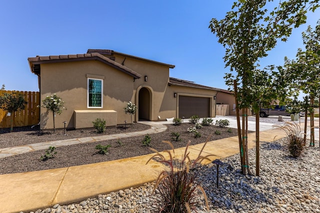 view of front of property with a garage, concrete driveway, fence, and stucco siding