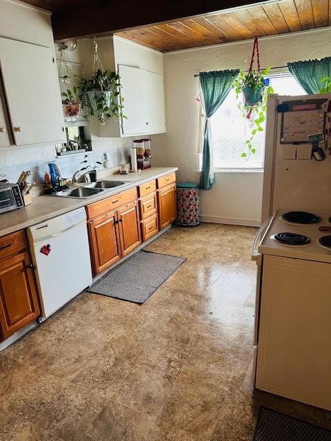 kitchen with a sink, white appliances, brown cabinetry, light countertops, and wood ceiling