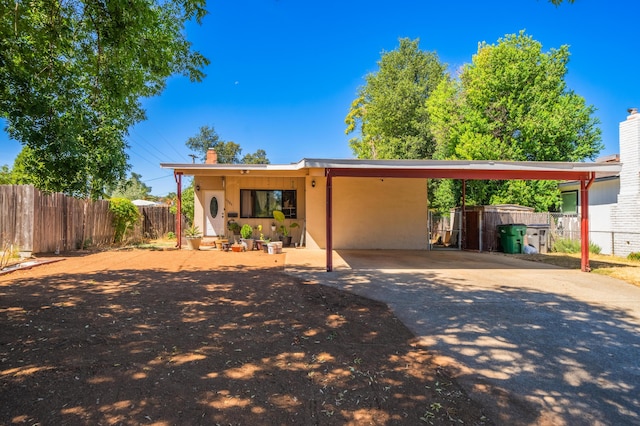 view of front facade with concrete driveway, fence, and a chimney