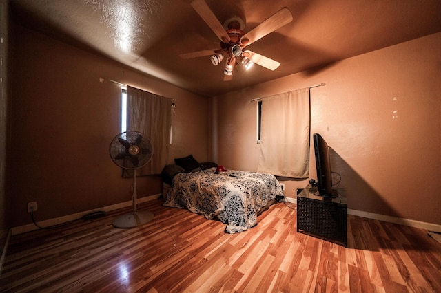 bedroom featuring a ceiling fan, baseboards, and wood finished floors