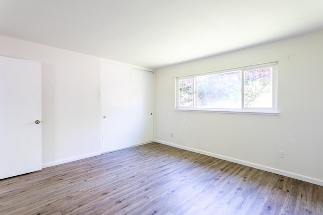 spare room with baseboards and wood finished floors