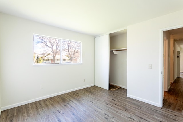 unfurnished bedroom featuring a closet, wood finished floors, and baseboards