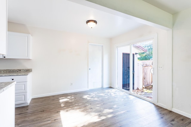 unfurnished dining area with light wood-style flooring and baseboards