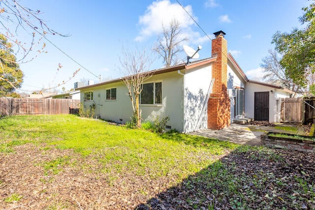 rear view of house with a lawn, a chimney, crawl space, fence, and stucco siding