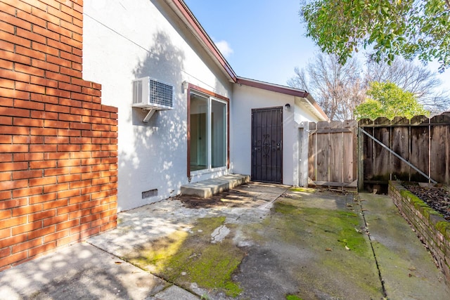 exterior space with a gate, fence, and a wall mounted air conditioner