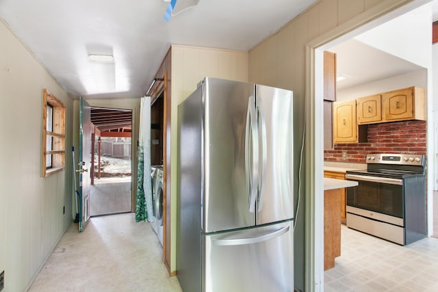 kitchen with separate washer and dryer, wood walls, light countertops, appliances with stainless steel finishes, and light floors