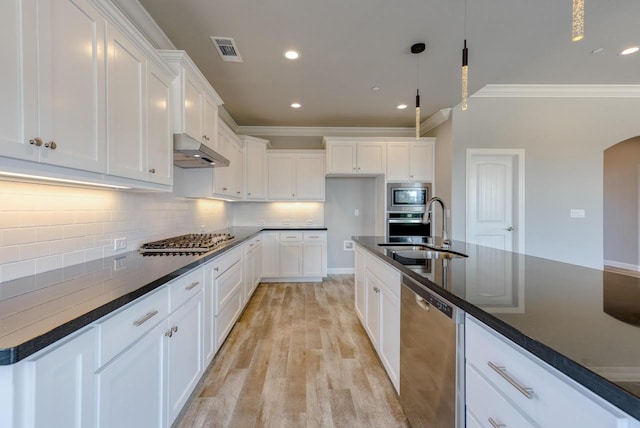 kitchen with arched walkways, visible vents, dark countertops, stainless steel appliances, and a sink