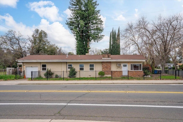 ranch-style house featuring stucco siding, a garage, and a fenced front yard