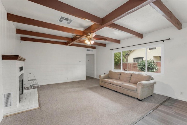 living room with beam ceiling, visible vents, and a fireplace