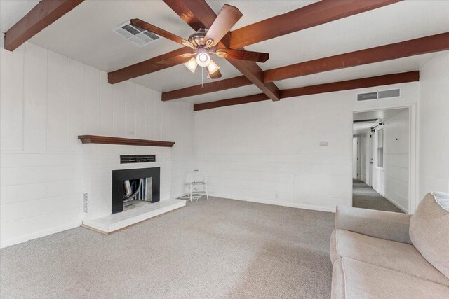 unfurnished living room with a fireplace, beamed ceiling, carpet, and visible vents