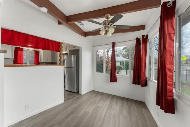 unfurnished dining area with wood finished floors, visible vents, baseboards, ceiling fan, and beamed ceiling