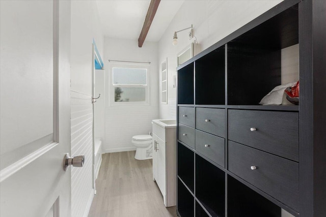 full bath featuring a washtub, toilet, beam ceiling, wood finished floors, and vanity