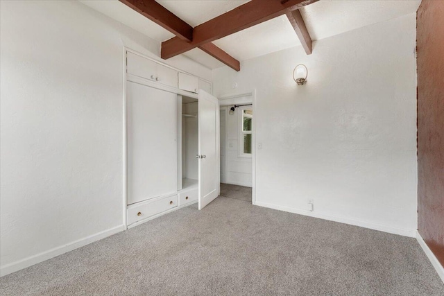 unfurnished bedroom featuring beam ceiling, carpet flooring, and baseboards