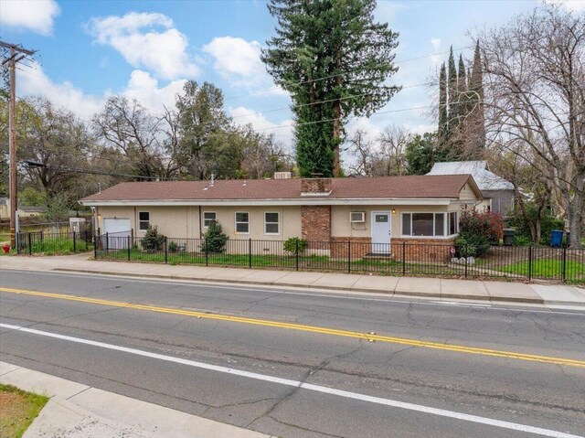 single story home with a wall mounted air conditioner, a fenced front yard, and stucco siding