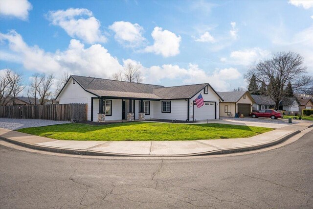 view of front of house with a garage, driveway, a front lawn, and fence