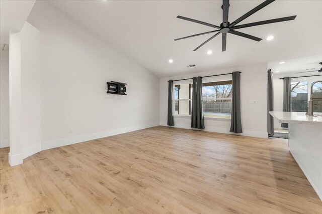 unfurnished living room featuring vaulted ceiling, light wood finished floors, visible vents, and a wealth of natural light