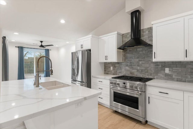 kitchen featuring light wood finished floors, stainless steel appliances, white cabinets, wall chimney range hood, and light stone countertops