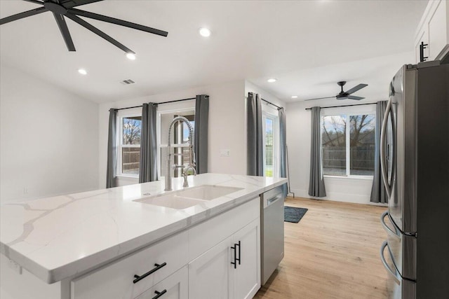 kitchen featuring light wood-style flooring, a sink, visible vents, a ceiling fan, and appliances with stainless steel finishes