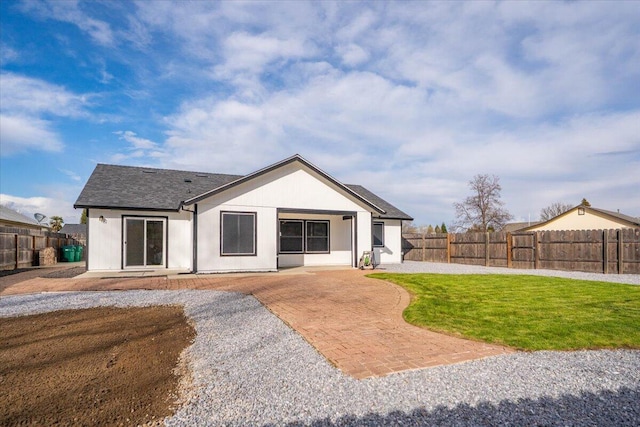 rear view of house with a fenced backyard, a yard, and a patio