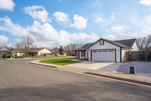 view of front facade featuring concrete driveway, a residential view, an attached garage, fence, and a front yard