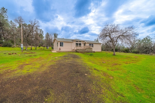 rear view of house featuring a yard and dirt driveway