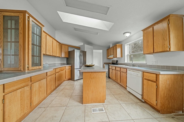 kitchen featuring a kitchen island, a sink, visible vents, appliances with stainless steel finishes, and tile counters