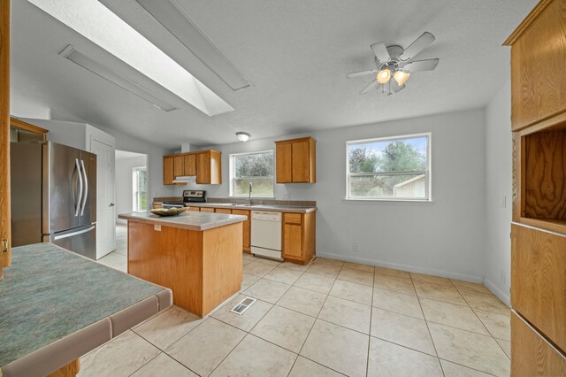 kitchen with light tile patterned flooring, stainless steel appliances, a skylight, a sink, and visible vents