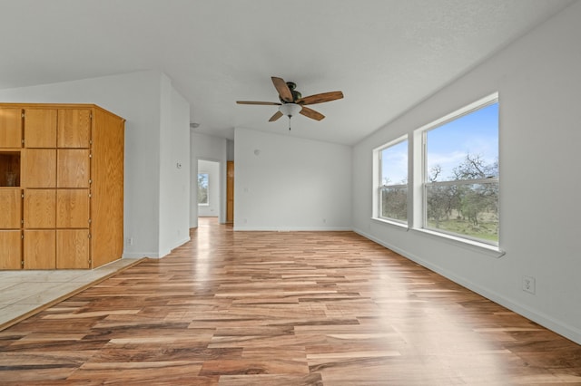 unfurnished living room featuring a ceiling fan, lofted ceiling, baseboards, and light wood finished floors