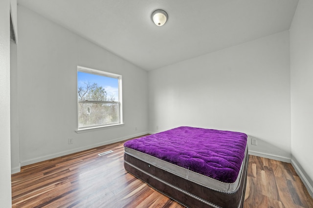 bedroom featuring visible vents, baseboards, vaulted ceiling, and wood finished floors