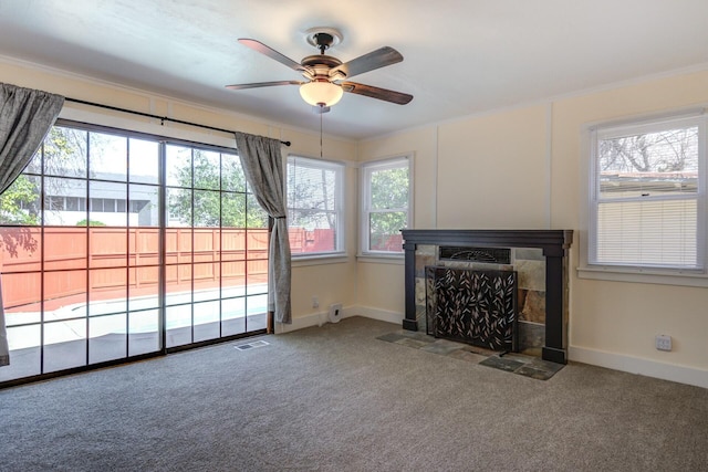 unfurnished living room with a tiled fireplace, carpet flooring, a healthy amount of sunlight, and visible vents