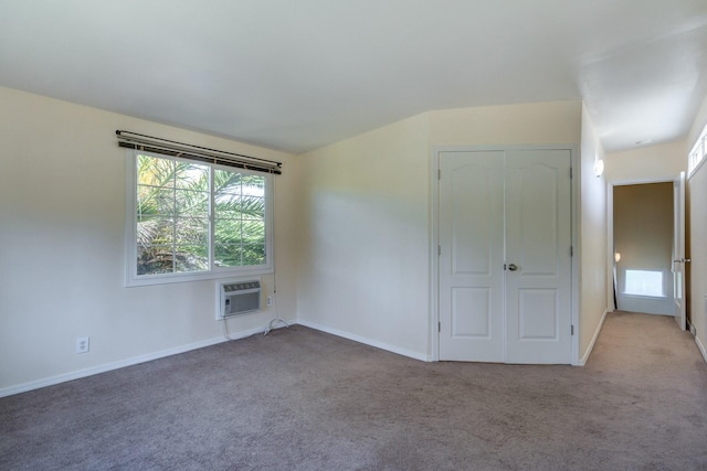 spare room with a wall mounted air conditioner, baseboards, and carpet floors