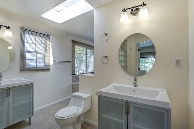 full bath featuring toilet, a skylight, two vanities, and a sink