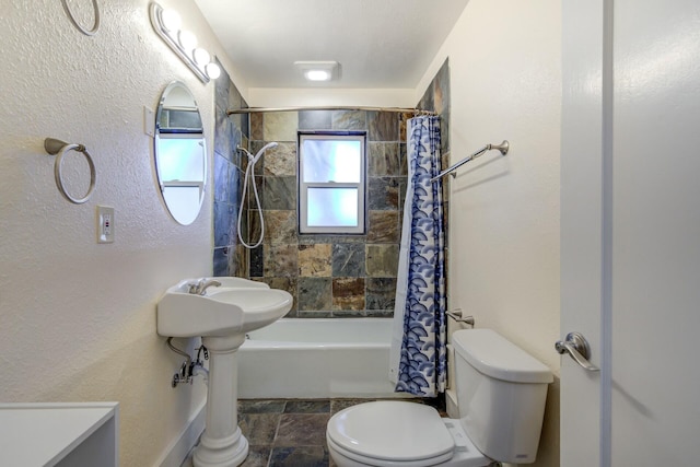 bathroom featuring stone finish flooring, toilet, and shower / tub combo with curtain