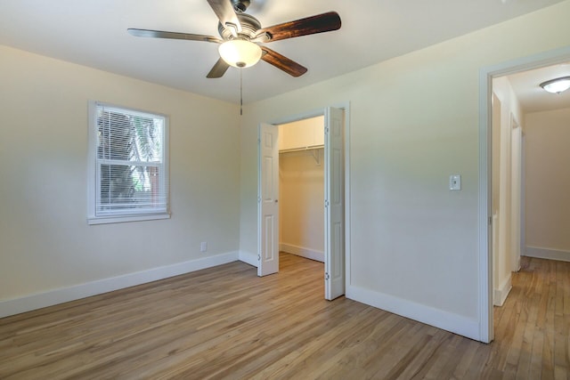 unfurnished bedroom featuring a ceiling fan, light wood-style floors, baseboards, and a closet