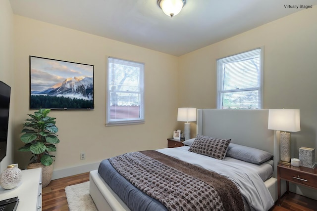 bedroom with multiple windows, dark wood-style floors, and baseboards