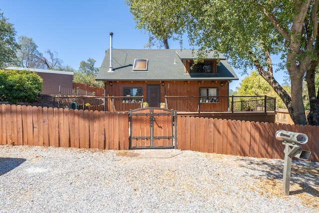 view of front of home featuring roof with shingles, a fenced front yard, and a gate